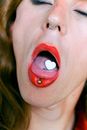 Piercing and pill on tongue of eccentric androgynous man with opened mouth
