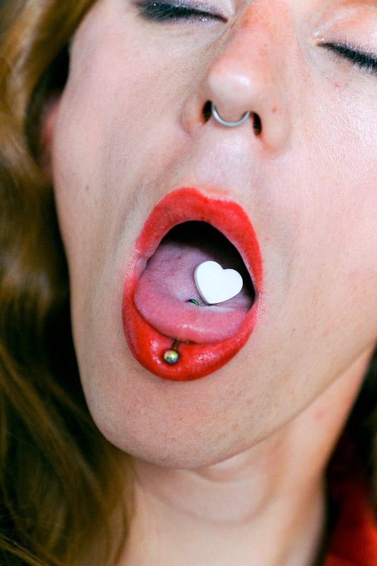 Piercing And Pill On Tongue Of Eccentric Androgynous Man With Opened Mouth