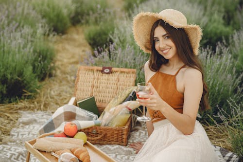 A Woman Sitting on a Picnic Blanket Holding a Glass of Wine