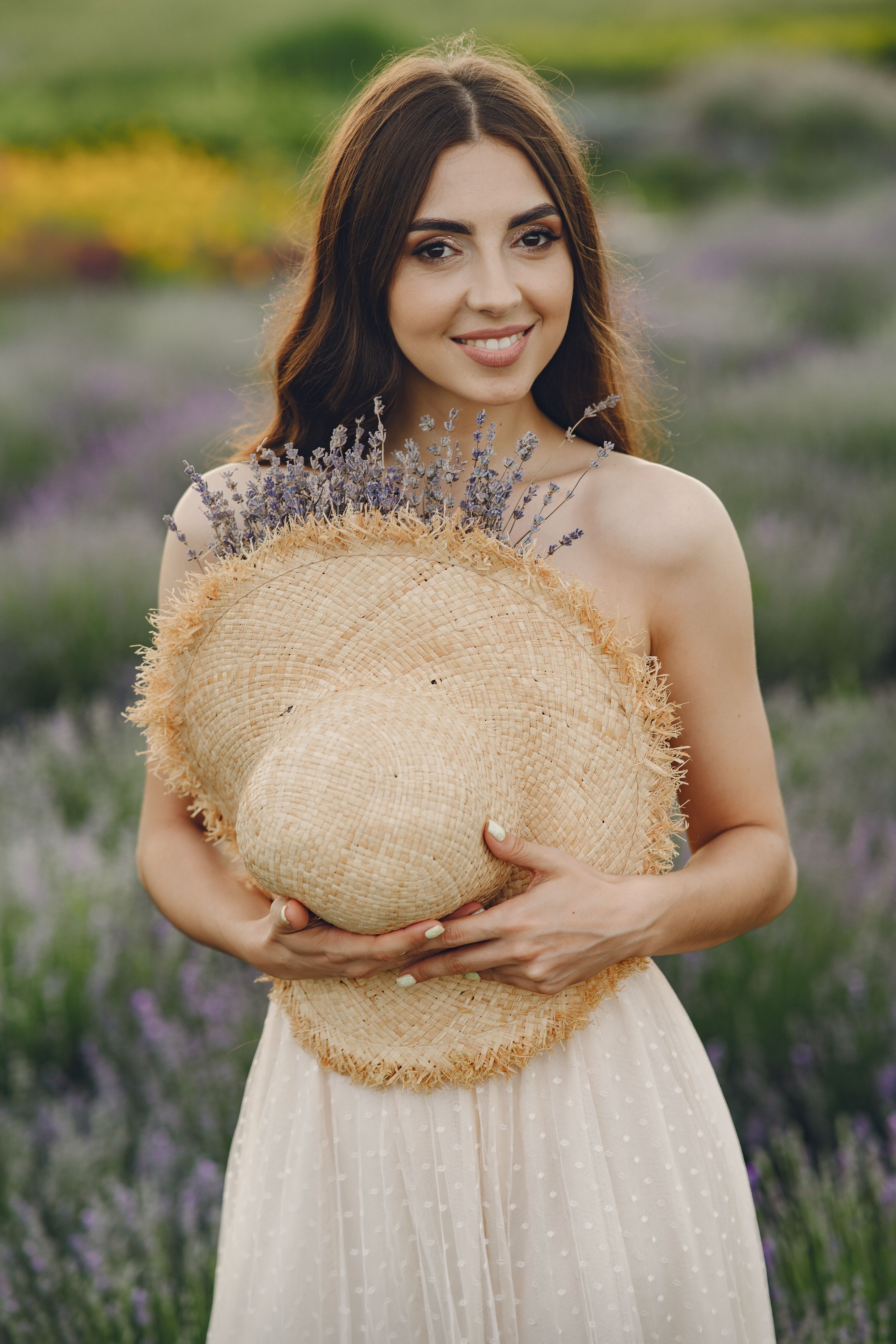 Woman Holding a Straw Hat With Purple Flowers · Free Stock Photo