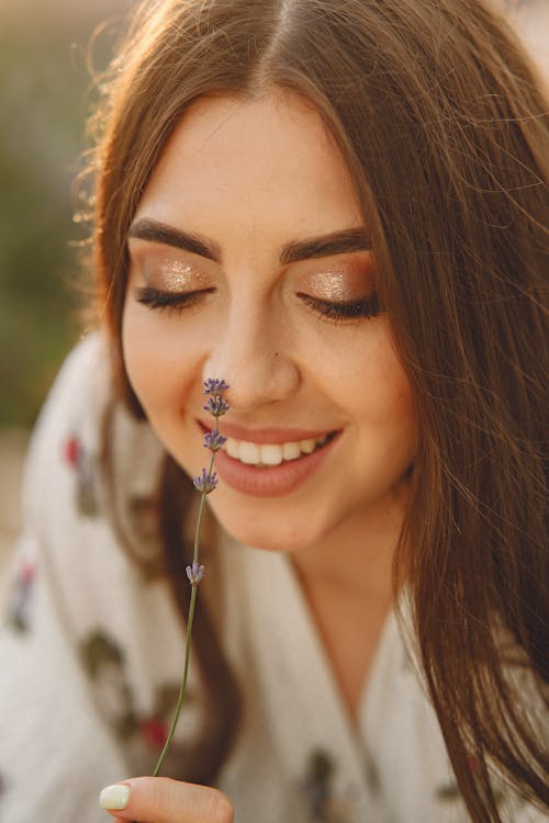 Free A Woman Sniffing a Purple Flower Stock Photo