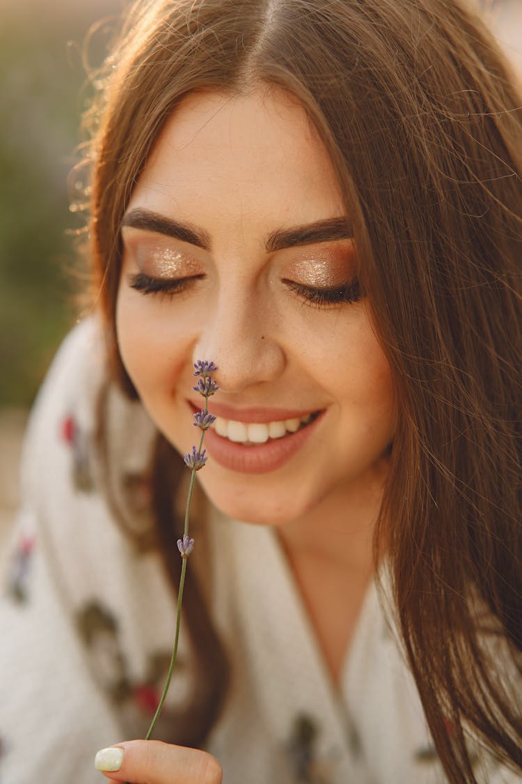 A Woman Sniffing A Purple Flower