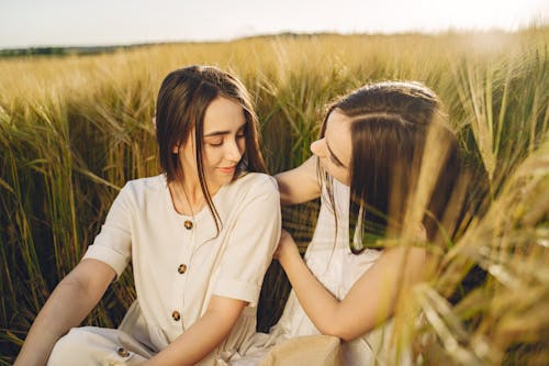 Free Two Women Sitting on a Grass Field Stock Photo