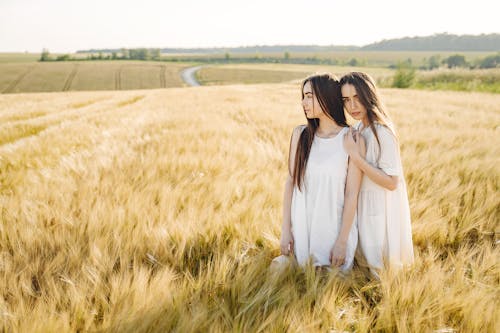 Women With Long Hair in White Dress Standing on Grass Field