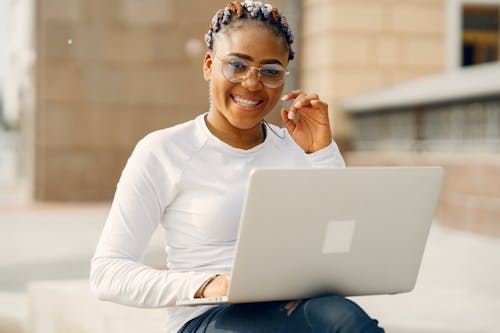 Free Woman in White Long Sleeve Shirt Wearing Eyeglasses Holding a Laptop Stock Photo