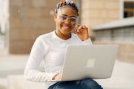 Woman in White Long Sleeve Shirt Wearing Eyeglasses Holding a Laptop