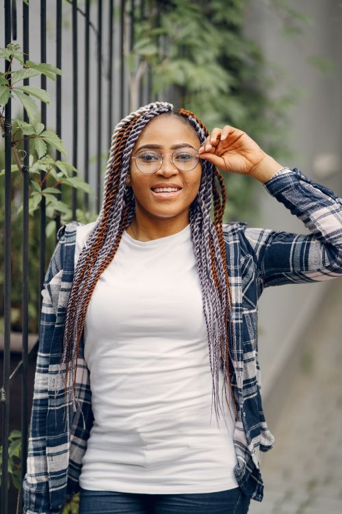 Free Young woman smiling and adjusting her glasses outdoors, dressed casually. Stock Photo