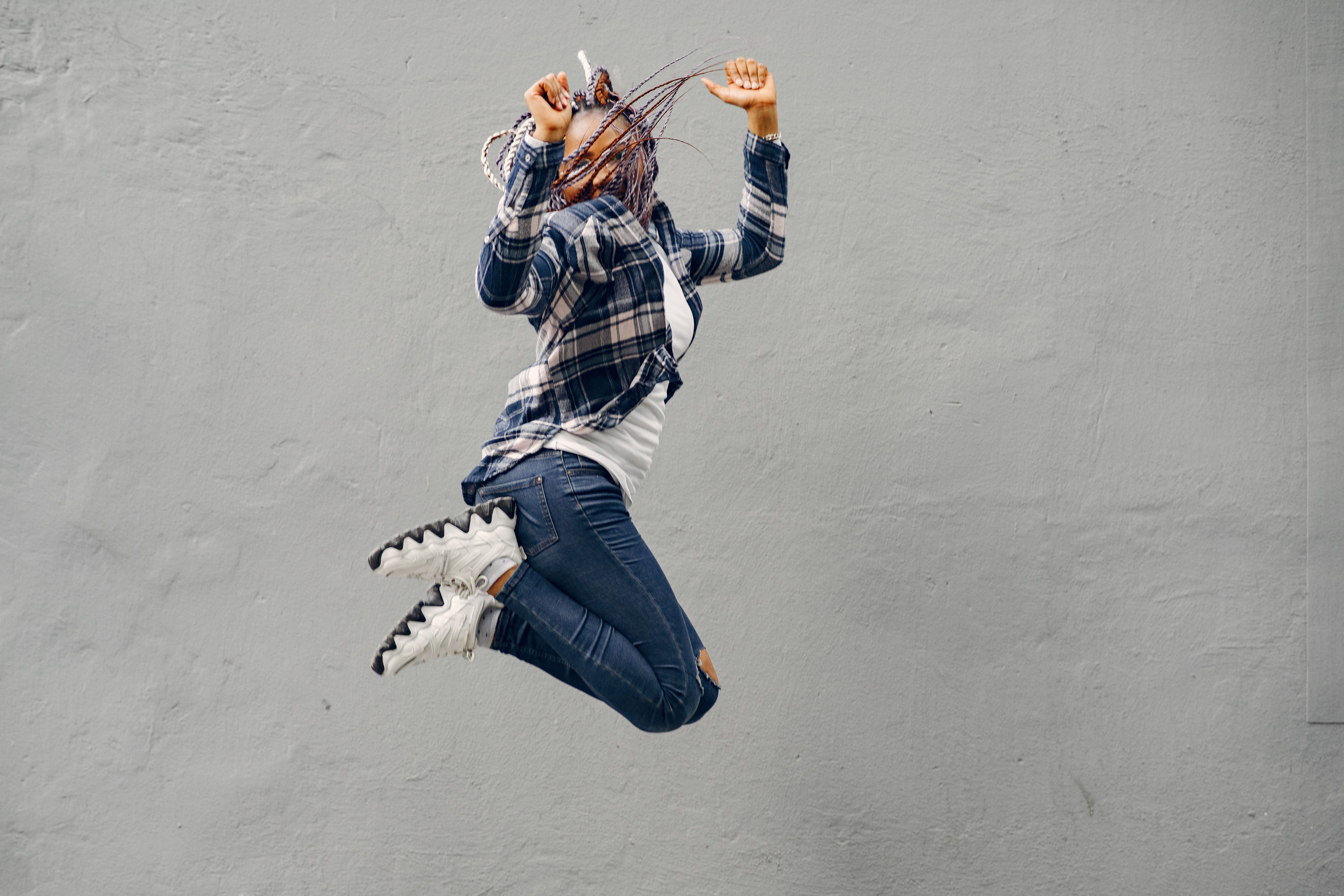 Dynamic shot of a woman mid-jump wearing casual fashion, capturing energy and freedom.