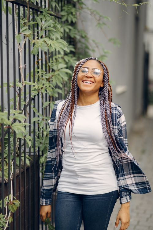 Free Smiling woman in a checkered shirt enjoying a sunny day outdoors, surrounded by nature. Stock Photo