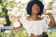 Woman with Afro Hairstyle and Large Earrings Holding a Cold Drink