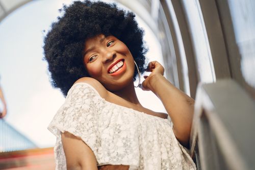 Free Joyful portrait of a woman with afro hair smiling brightly under clear skies. Stock Photo