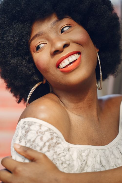 Free Close-up portrait of a beautiful woman with afro hair, smiling and looking sideways in natural light. Stock Photo