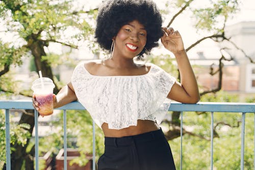 Woman in a White Crop Top Holding a Drink while Smiling