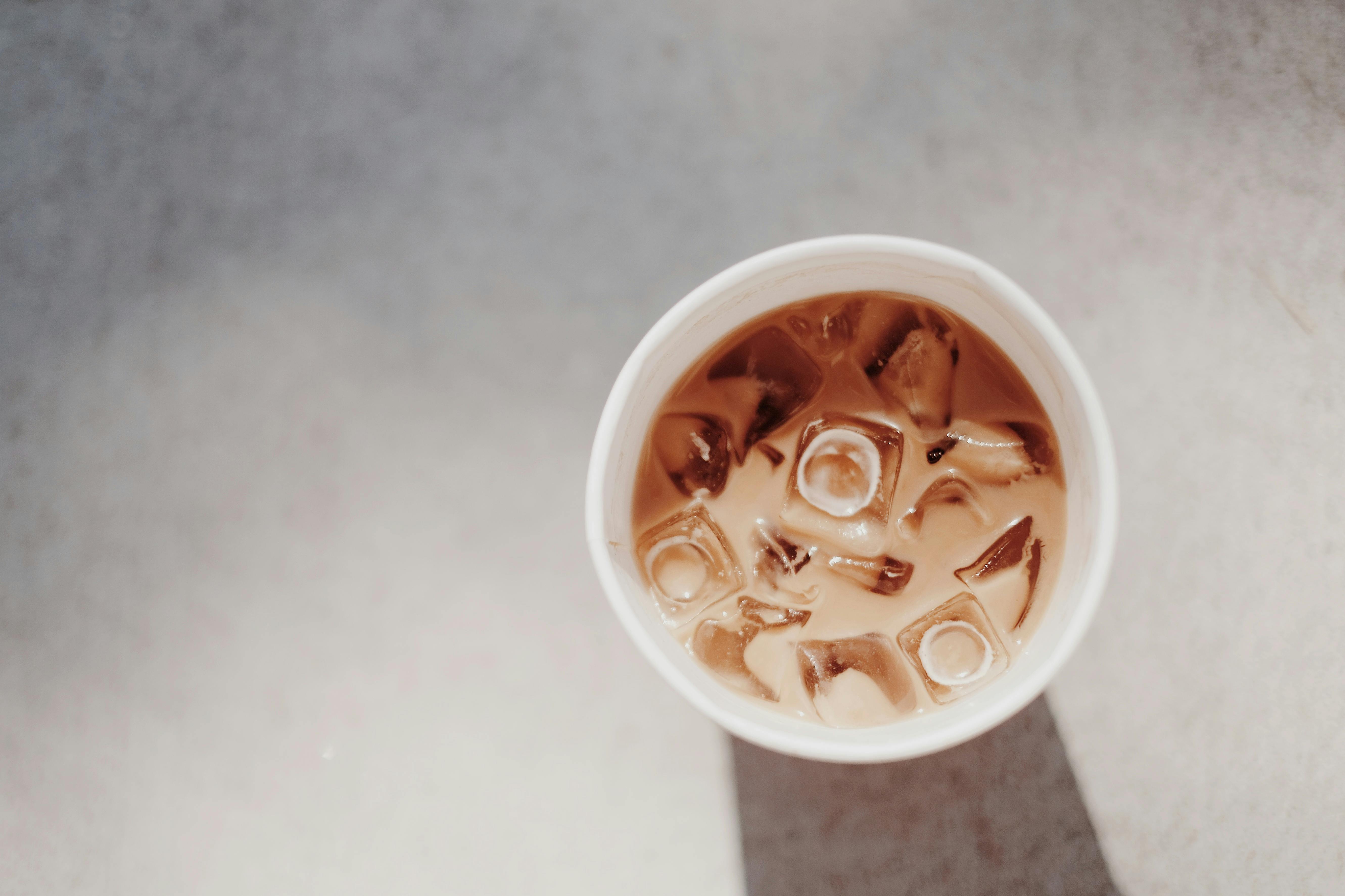 A minimalist top view of a refreshing iced coffee in a cup with natural lighting and shadows.