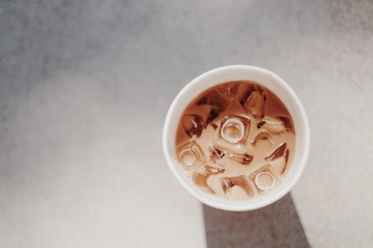 A minimalist top view of a refreshing iced coffee in a cup with natural lighting and shadows.