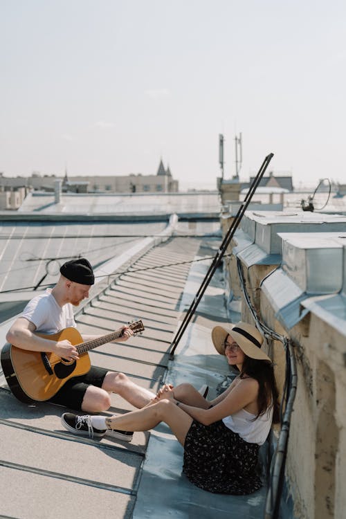 2 Women Sitting on White and Brown Boat Playing Guitar