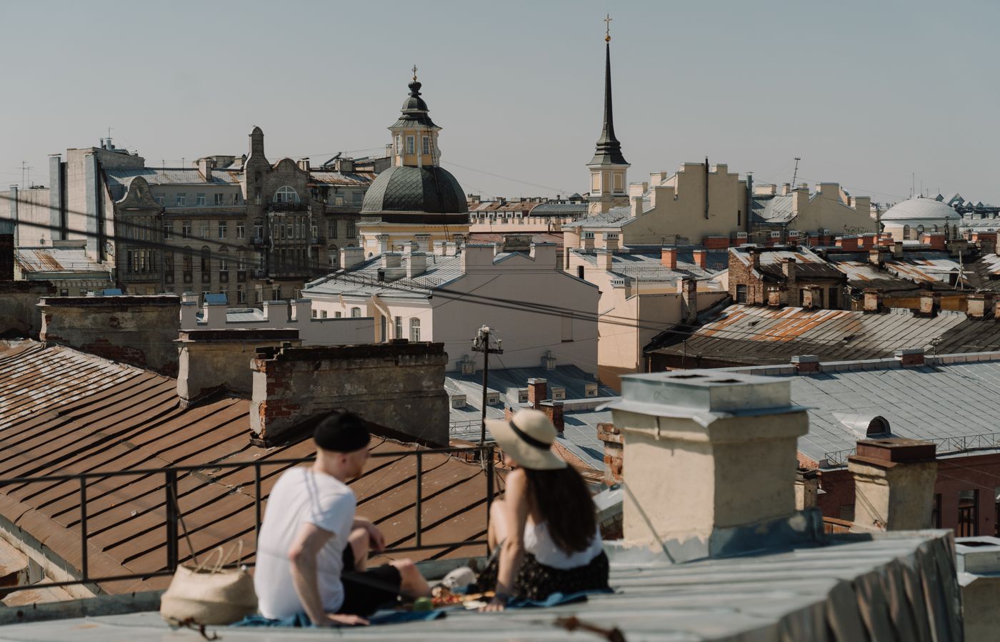 A couple relaxes on a rooftop overlooking a scenic old town cityscape.