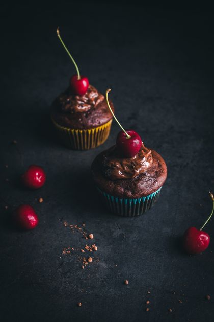 Chocolate cupcakes topped with cherries on a dark background — Sangeeth N on Pexels