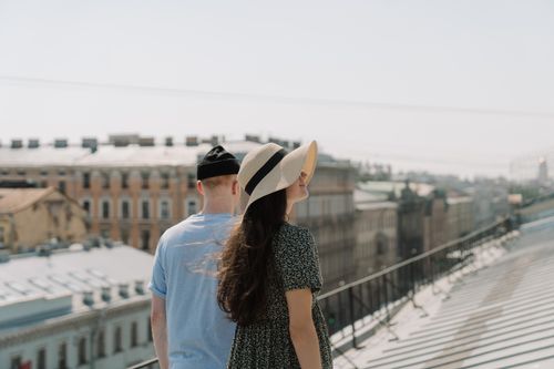 Free A young couple enjoys a romantic moment on a city rooftop, surrounded by historic buildings. Stock Photo