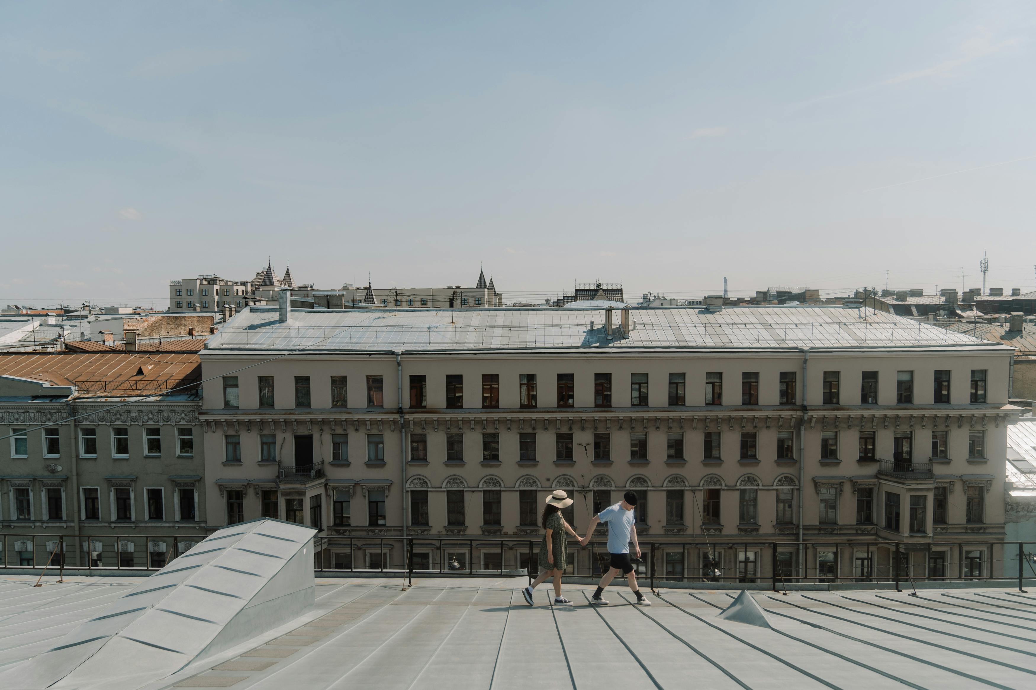 A young couple holds hands on a city rooftop, embracing a sunny day together.