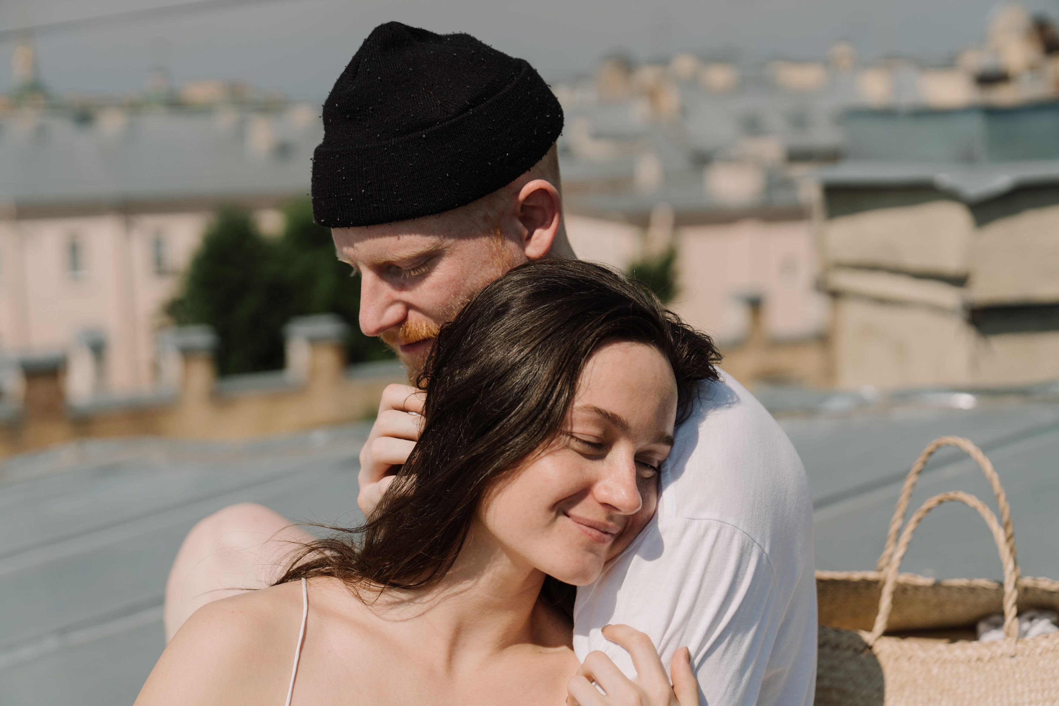 A loving couple shares a tender moment embracing on a sunny rooftop.
