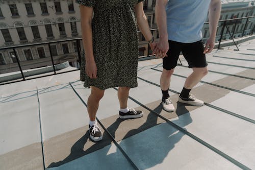 Mujer En Vestido Blanco Y Negro De Pie Junto Al Hombre Con Camisa Azul