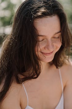 一位长发女子微笑着，在户外享受着阳光明媚的一天