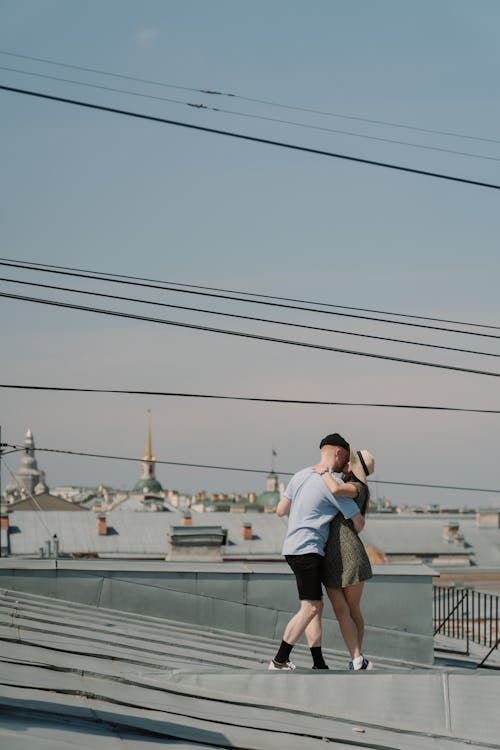 Woman in White Shirt and Black Shorts Standing on Roof Top