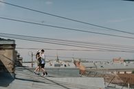 在晴朗的夏日天空下，一对年轻夫妇在俯瞰城市景观的屋顶上共享了浪漫时刻