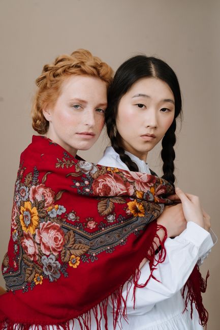 Portrait of two women wearing traditional floral shawl, showcasing cultural diversity and beauty.