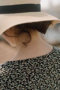 夏日户外，一名身穿花卉连衣裙、头戴遮阳帽的女子正享受悠闲时光