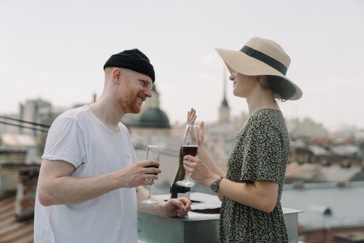 A couple enjoying a romantic moment with wine on a rooftop overlooking a cityscape.