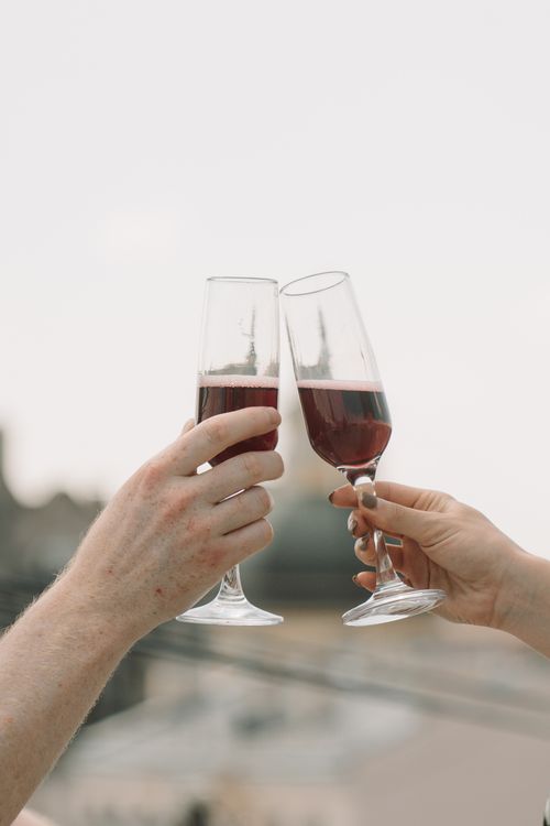 Free Two people clinking wine glasses outdoors in a romantic setting. Stock Photo