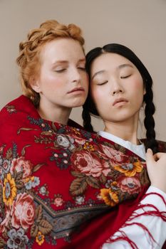 两名女子身穿传统花卉披肩，拥抱在一起