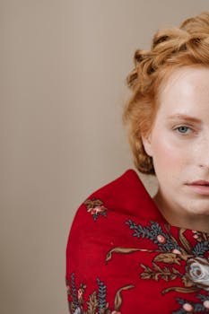 一幅披着传统红色花卉披肩的特写肖像，背景为米色