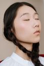 中性背景下，一个扎着辫子、闭着眼睛的女人特写，散发着平静