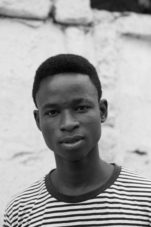 Free Monochrome portrait of a teenage boy with a striped shirt, looking directly at the camera. Stock Photo