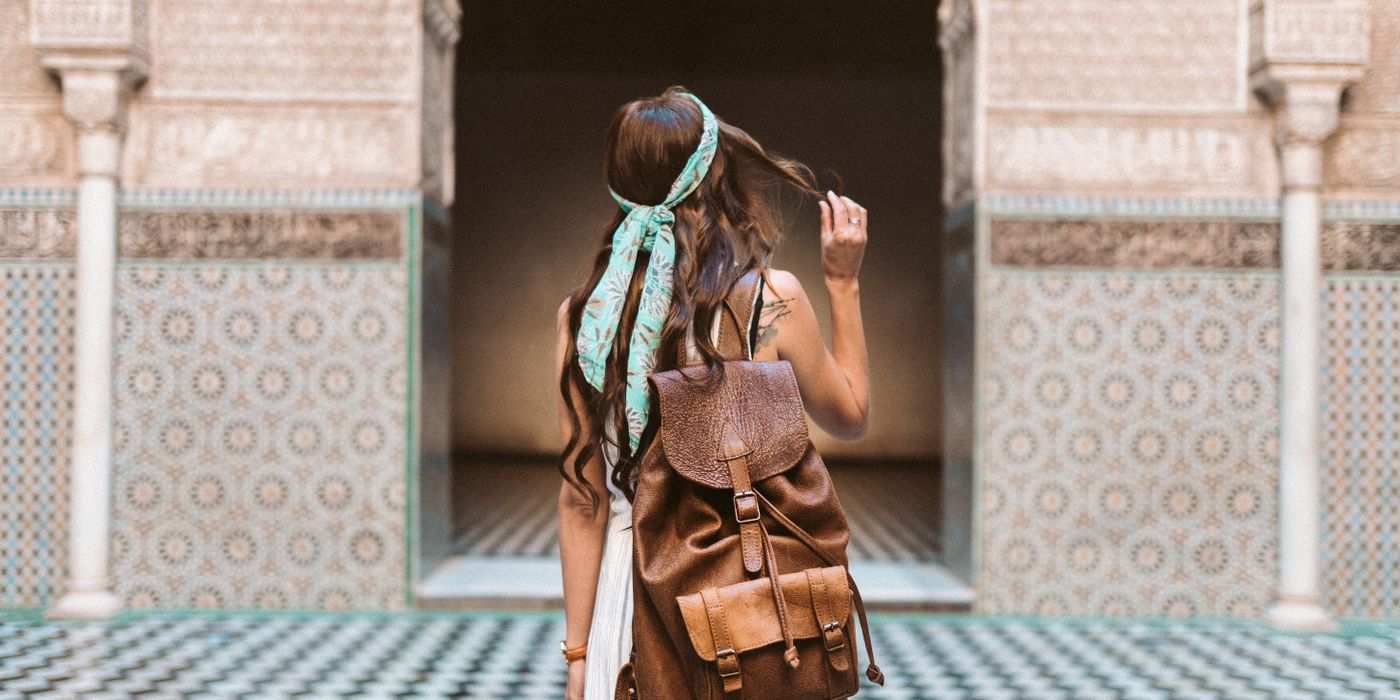 Woman solo traveler exploring a city street independently with a backpack