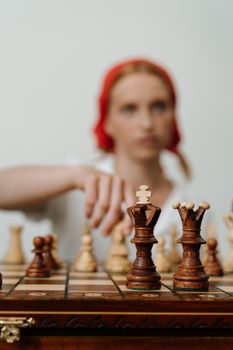 一个女人正专注于木制棋盘，策划着她的下一步棋
