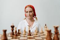 一位红发女子戴着头巾，正专注于自己的策略下着国际象棋