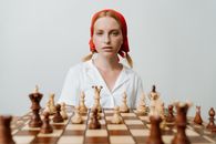 一位头戴红巾的女子正专注地思考着棋局