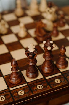 Close-up view of intricately carved wooden chess pieces on a chessboard, showcasing strategy and craftsmanship.