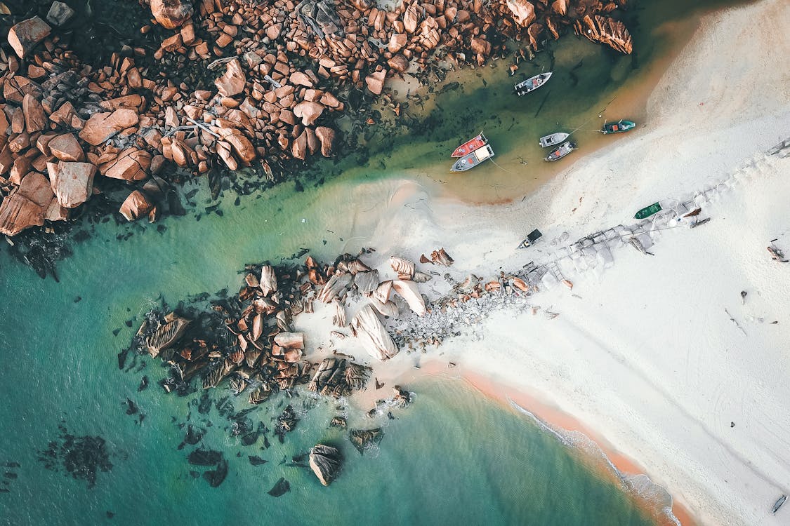 Free Boats floating in water near rocky shore Stock Photo