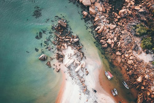Free Sandy shore with rocks and floating boats Stock Photo