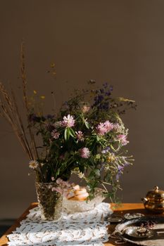 一幅静物画中，美丽的野花与俄罗斯蕾丝和茶壶相映成趣