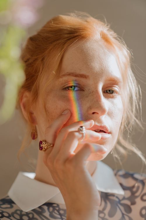 Free Portrait of a redheaded woman with elegant jewelry and rainbow light across her face. Stock Photo