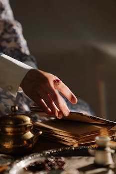 一只戴着红宝石戒指的优雅手，正翻动一本古董书的书页，特写镜头非常适合高贵经典的主题