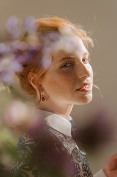 这幅迷人的肖像画描绘了一位优雅的红发女性，她周围环绕着柔焦的花朵