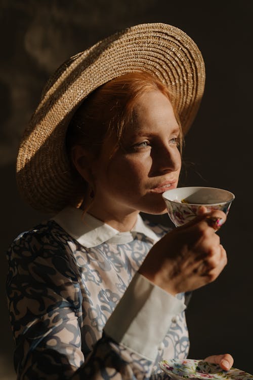 Woman in Blue and White Floral Shirt Holding White Ceramic Mug