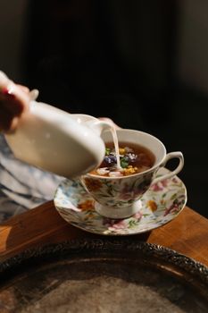 将牛奶倒入迷人的花香茶具，展现出精致的优雅与风格